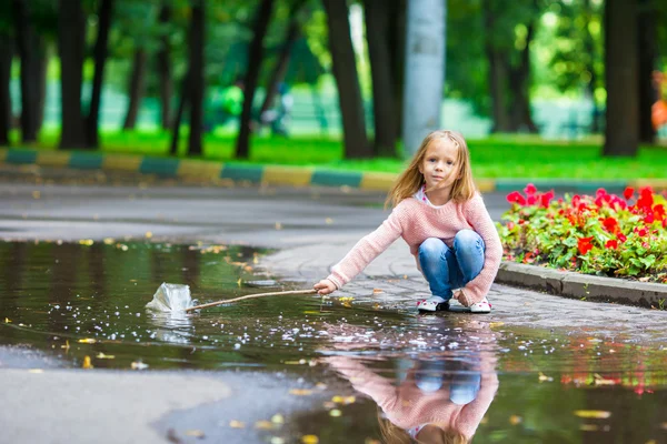 Petite fille heureuse s'amuser dans une grande flaque d'eau dans le parc d'automne — Photo