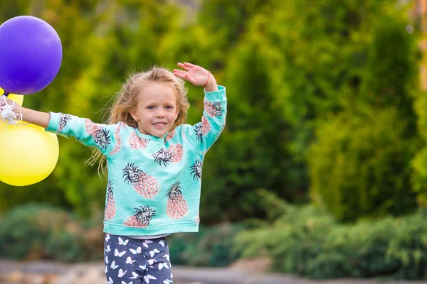 Glückliches kleines Mädchen, das draußen mit Luftballons spielt — Stockfoto