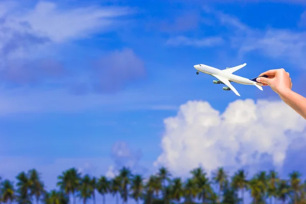 Petit modèle d'avion blanc en fond de main féminine de mer turquoise — Photo