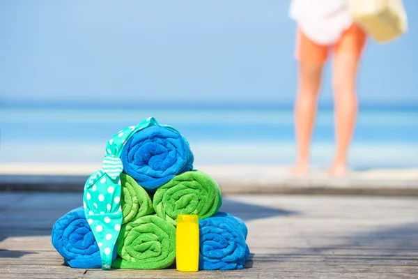 Spiaggia e accessori estate concetto asciugamani colorati, costume da bagno e crema solare sfondo bella donna — Foto Stock