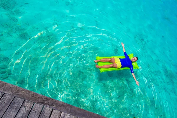 Junger glücklicher Mann entspannt sich auf aufblasbarer Matratze im Meer — Stockfoto