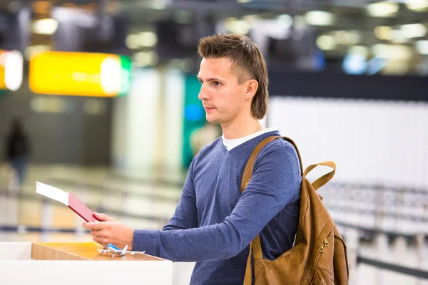 Young man with passports and boarding passes at the front desk at airport — Stock Photo, Image