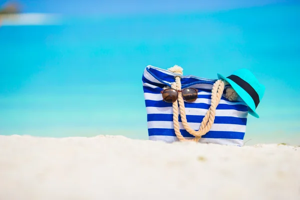 Plážové doplňky - modrá taška, slaměný klobouk, sluneční brýle na bílé pláži — Stock fotografie