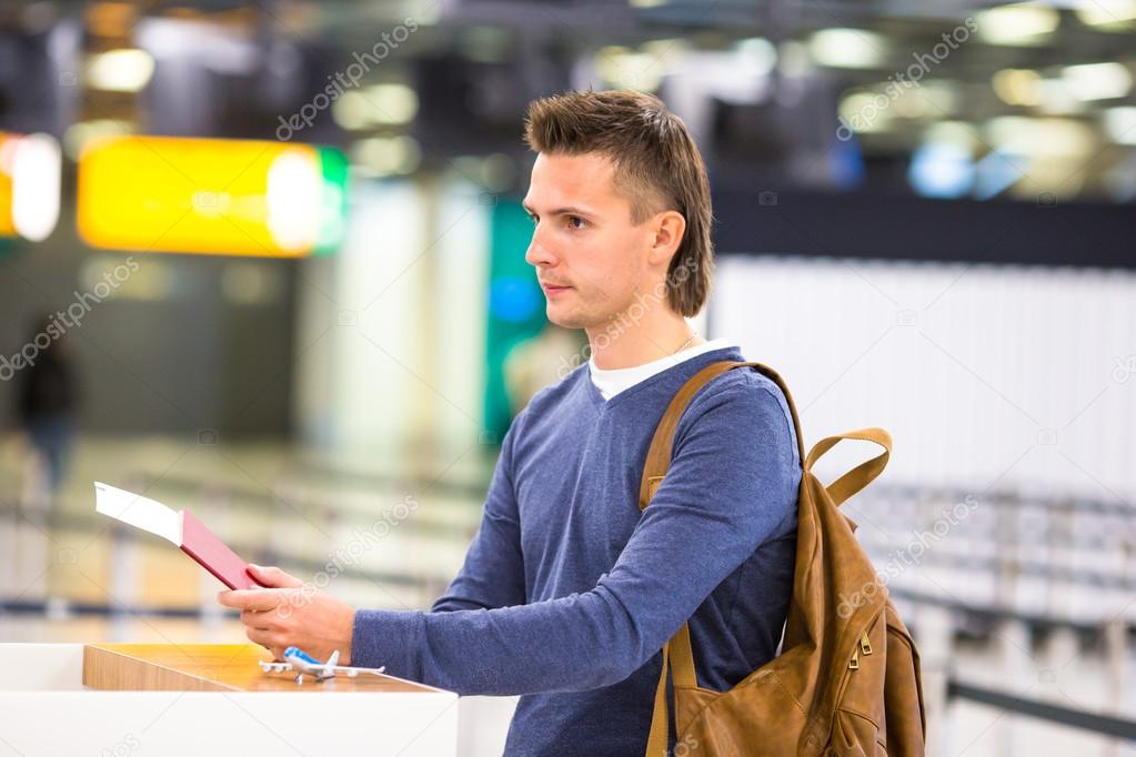 Young man with passports and boarding passes at the front desk at airport
