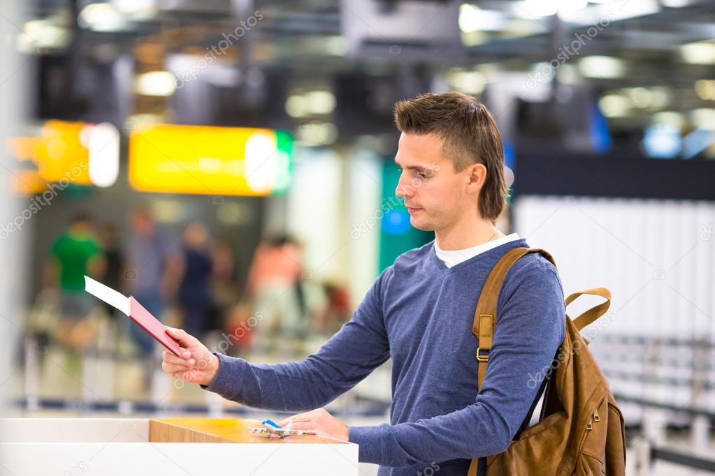 Young man with passports and boarding passes at the front desk at airport