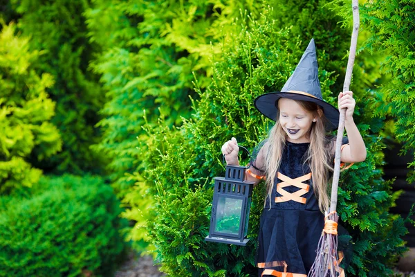 Rozkošná holčička v kostýmu čarodějnice s koštětem na Halloween venku — Stock fotografie