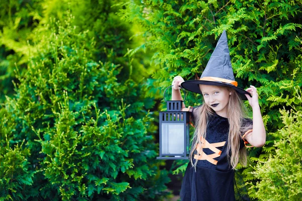 Adorável menina vestindo traje de bruxa com vassoura no Halloween ao ar livre — Fotografia de Stock