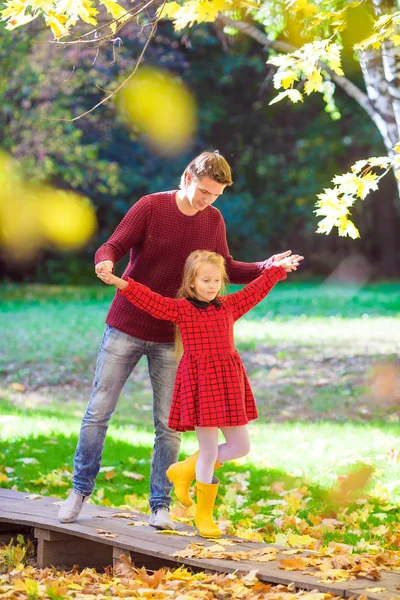 Sevimli küçük kız eğleniyor sonbahar park güneşli bir günde mutlu baba ile — Stok fotoğraf