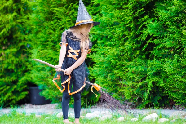 Adorable niña usando traje de bruja con escoba en Halloween al aire libre — Foto de Stock