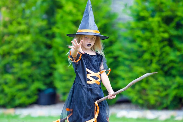 Imádnivaló kislány boszorkányjelmezt visel seprűvel Halloweenkor. — Stock Fotó
