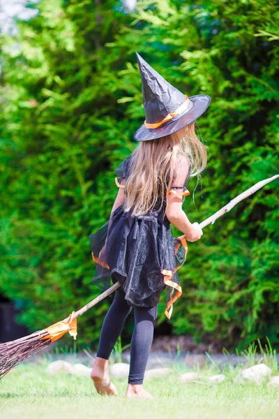 Adorable little girl wearing witch costume with broom having fun on Halloween — Stock Photo, Image