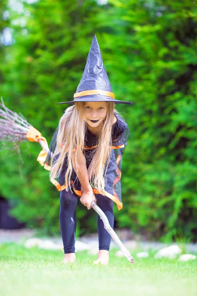 Adorable little girl wearing witch costume with broom having fun on Halloween — Stock Photo, Image