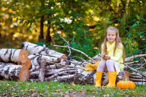 Bedårande liten flicka med en pumpa till Halloween utomhus på vacker höstdag — Stockfoto