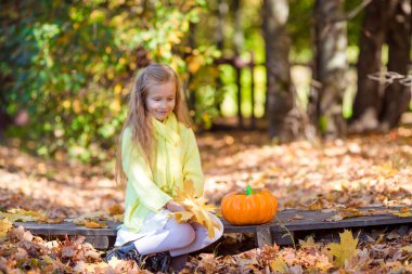Sevimli küçük kız için açık havada güzel sonbahar günü Halloween balkabağı ile