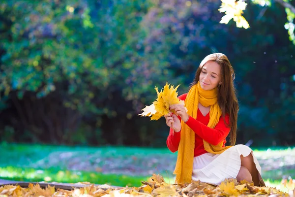 Счастливая молодая женщина с желтыми листьями клена на открытом воздухе в красивом осеннем парке — стоковое фото