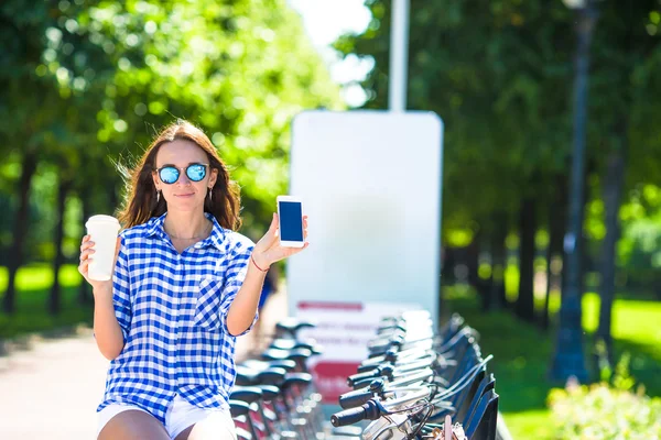 Young woman with glass of coffee on bicycle outdoor — Stock Photo, Image