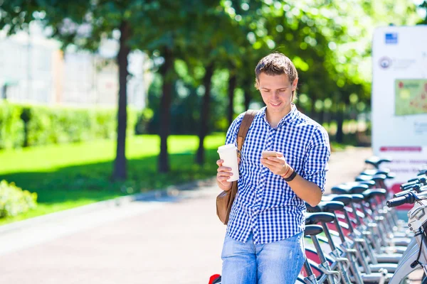 Jeune homme avec verre de café à vélo en plein air — Photo