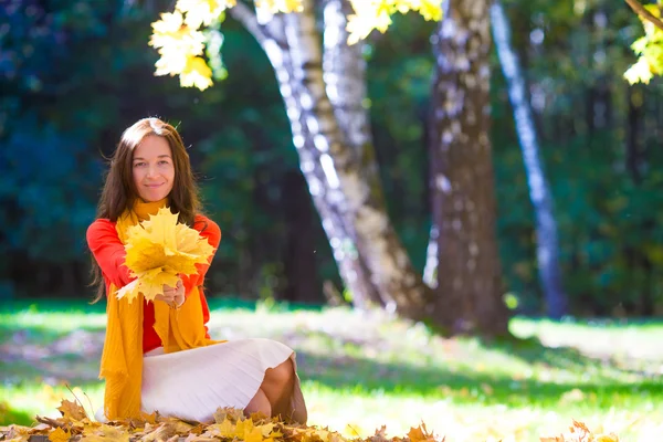 Счастливая молодая женщина с желтыми листьями клена на открытом воздухе в красивом осеннем парке — стоковое фото