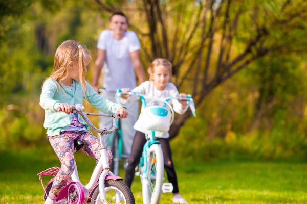 Семья молодого отца и маленьких детей катаются на велосипеде в летний теплый день — стоковое фото