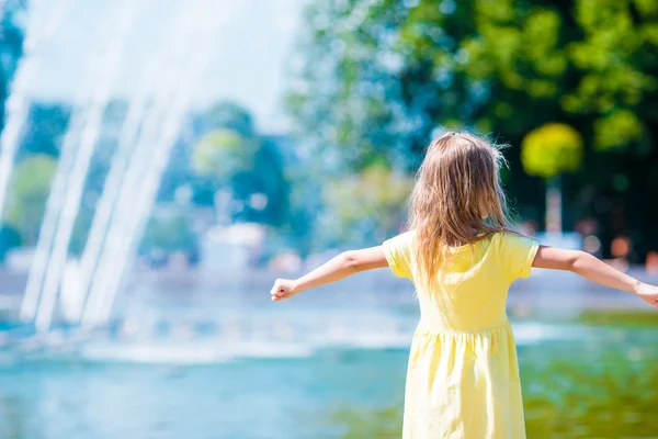 Liten glad tjej ha roligt nära gatan fontänen på varm solig dag — Stockfoto