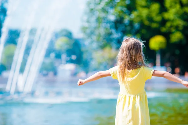 Niña feliz divertirse cerca de la fuente de la calle en el día soleado caliente —  Fotos de Stock