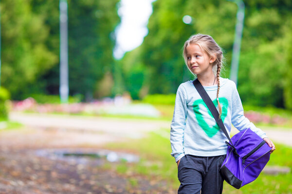 Маленькая очаровательная девочка идет в спортзал со своей спортивной сумкой
