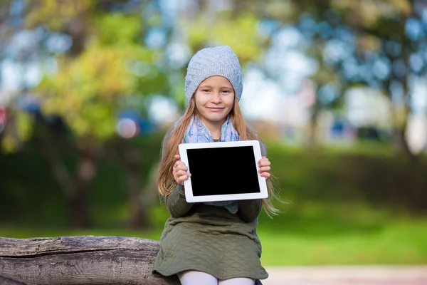 Bedårande liten flicka håller tablet Pc utomhus i soliga höstdag — Stockfoto