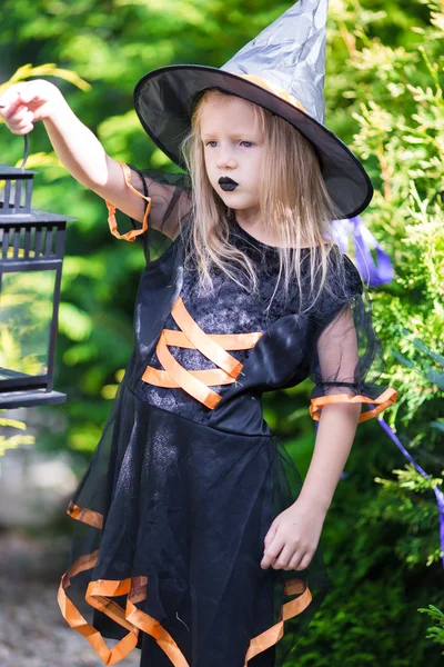 Adorable niña divertida con traje de bruja en Halloween al aire libre. Truco o trato . —  Fotos de Stock