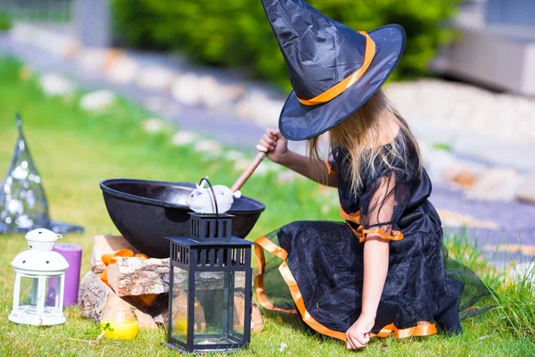 Menina adorável vestindo trajes de bruxa lançando um feitiço no Halloween. Doce ou travessura . — Fotografia de Stock