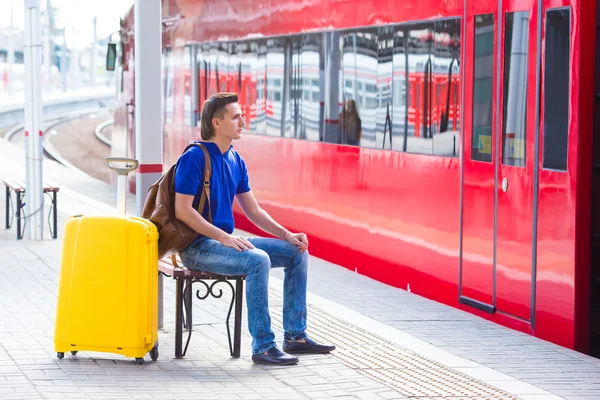 Молодой человек с багажом на вокзале рядом с экспрессом — стоковое фото