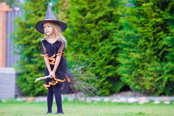 Menina adorável vestindo traje de bruxa no Halloween ao ar livre. Doce ou travessura . — Fotografia de Stock