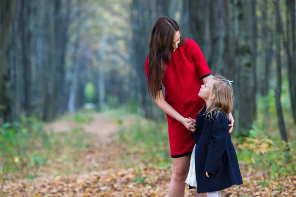 Bedårande liten flicka med mamma i höst park utomhus — Stockfoto