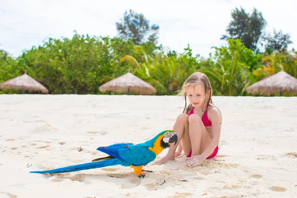 Adorable happy little girl with colorful parrot during beach vacation — Stock Photo, Image