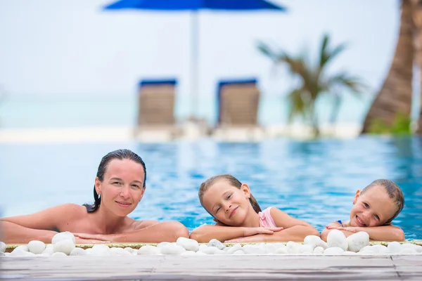 Mother and two little kids enjoying summer vacation in luxury swimming pool — Stock Photo, Image