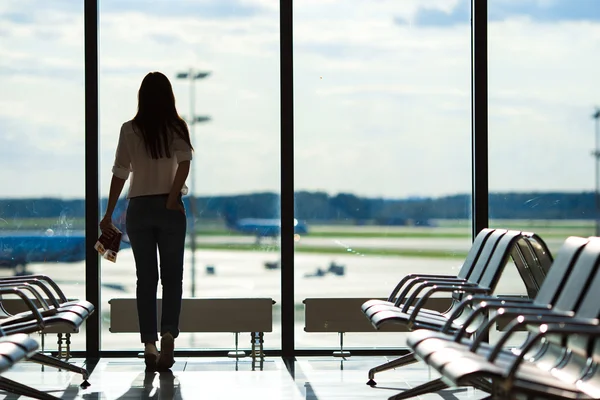 Mujer joven cerca de la ventana en un salón del aeropuerto esperando aviones de vuelo —  Fotos de Stock