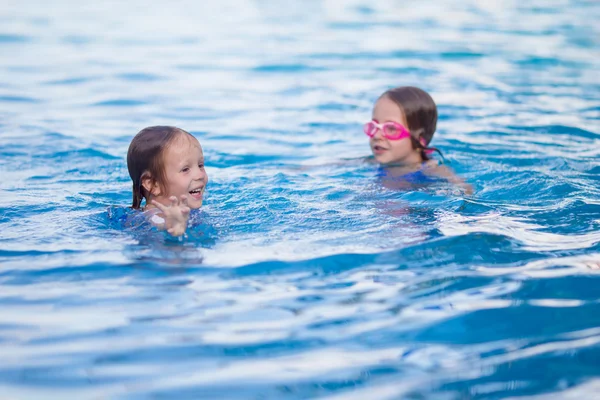 Adorable little girls playing in outdoor swimming pool on vacation — Stock Photo, Image