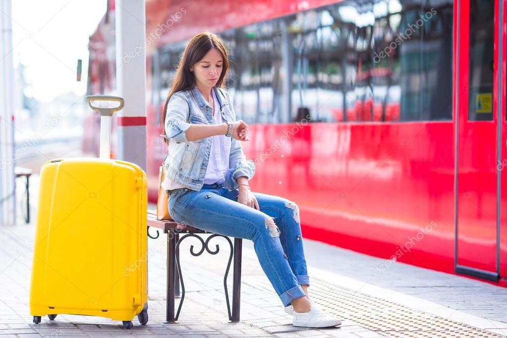 Young woman with luggage on train platform waiting for aeroexpress