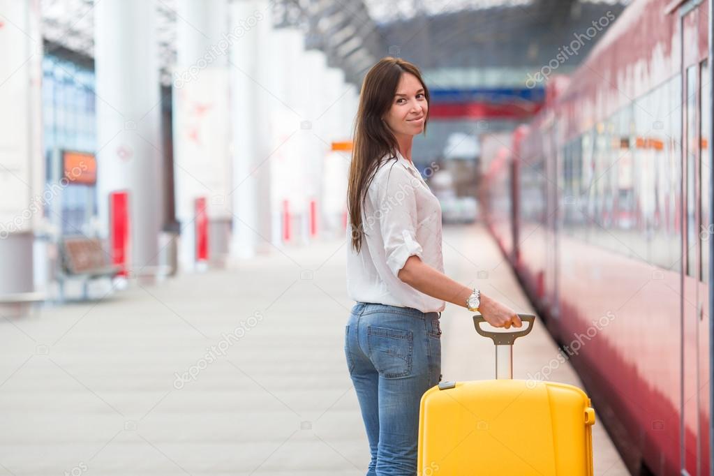 Young woman with luggage on train platform waiting for aeroexpress