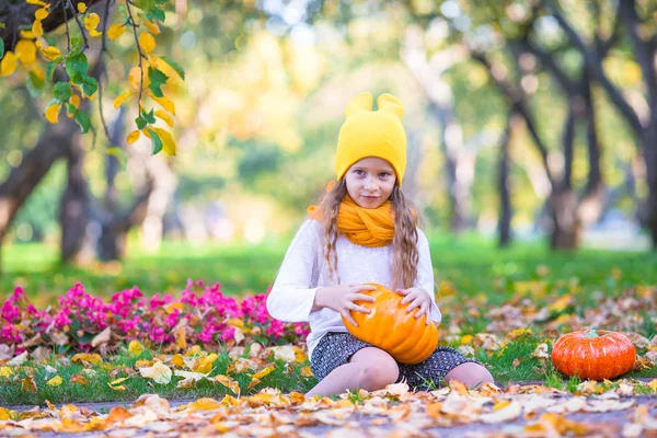 Adorable little girl with pumpkin outdoors at beautiful autumn day. Trick or treat — Stock Photo, Image