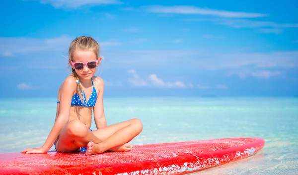 Little adorable girl on surfboard in turquoise sea — Stock Photo, Image