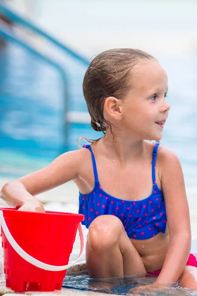 Weinig gelukkig schattig meisje met strand speelgoed in zwembad buiten — Stockfoto