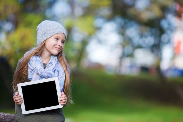 Adorável menina segurando tablet PC ao ar livre no outono dia ensolarado — Fotografia de Stock