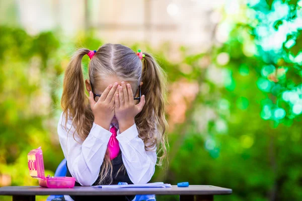 Menina da escola adorável na mesa com notas e lápis ao ar livre. De volta à escola . — Fotografia de Stock