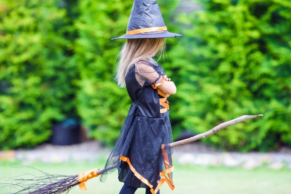 Schattig meisje in halloween kostuum plezier op een bezemsteel. Trick or treat. — Stockfoto