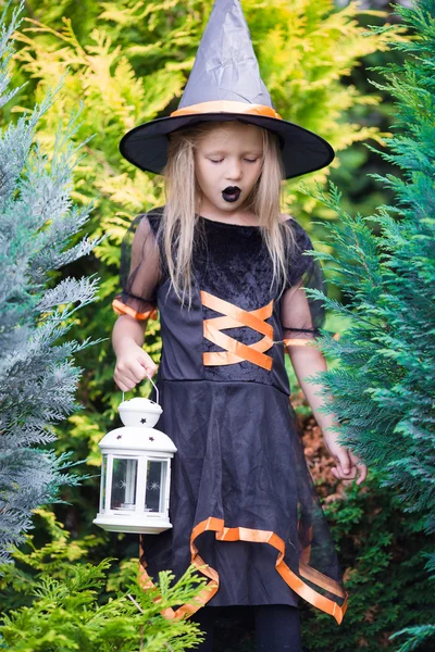 Adorable amasing little girl wearing witch costume on Halloween. Trick or treat.