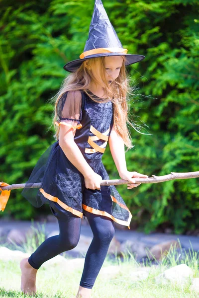 Šťastná holčička s koštětem na sobě čarodějnice kostým na Halloween. Pořád to samý. — Stock fotografie