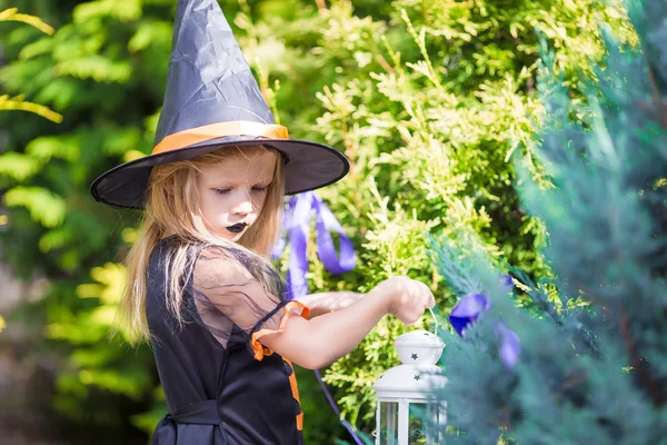 Halloween a Rozkošná holčička s svíčka oblečený jako čarodějnice — Stock fotografie