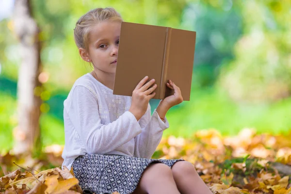 Aranyos kislány, olvasson egy könyvet gyönyörű őszi park — Stock Fotó