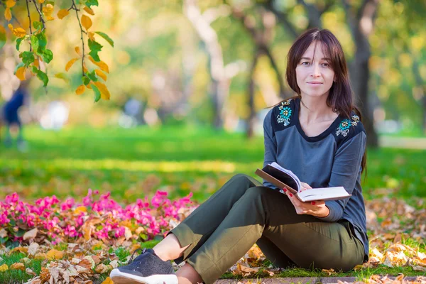 Молодая женщина читает книгу в красивом осеннем парке — стоковое фото
