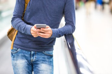 Sırt çantası uçuş bekliyor havaalanında cep telefonu tutan adamla